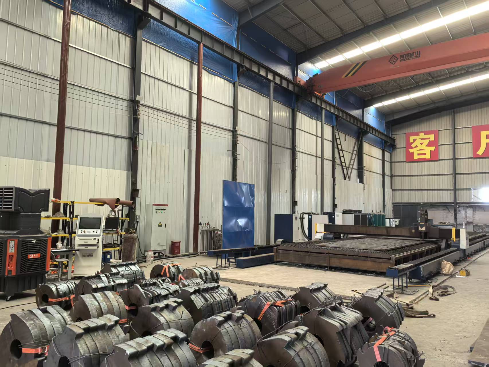 Complete workshop equipment for steel plate supply and custom laser cutting service Full CNC fiber laser cutting production line inside our steel processing factory with raw steel coils in stock