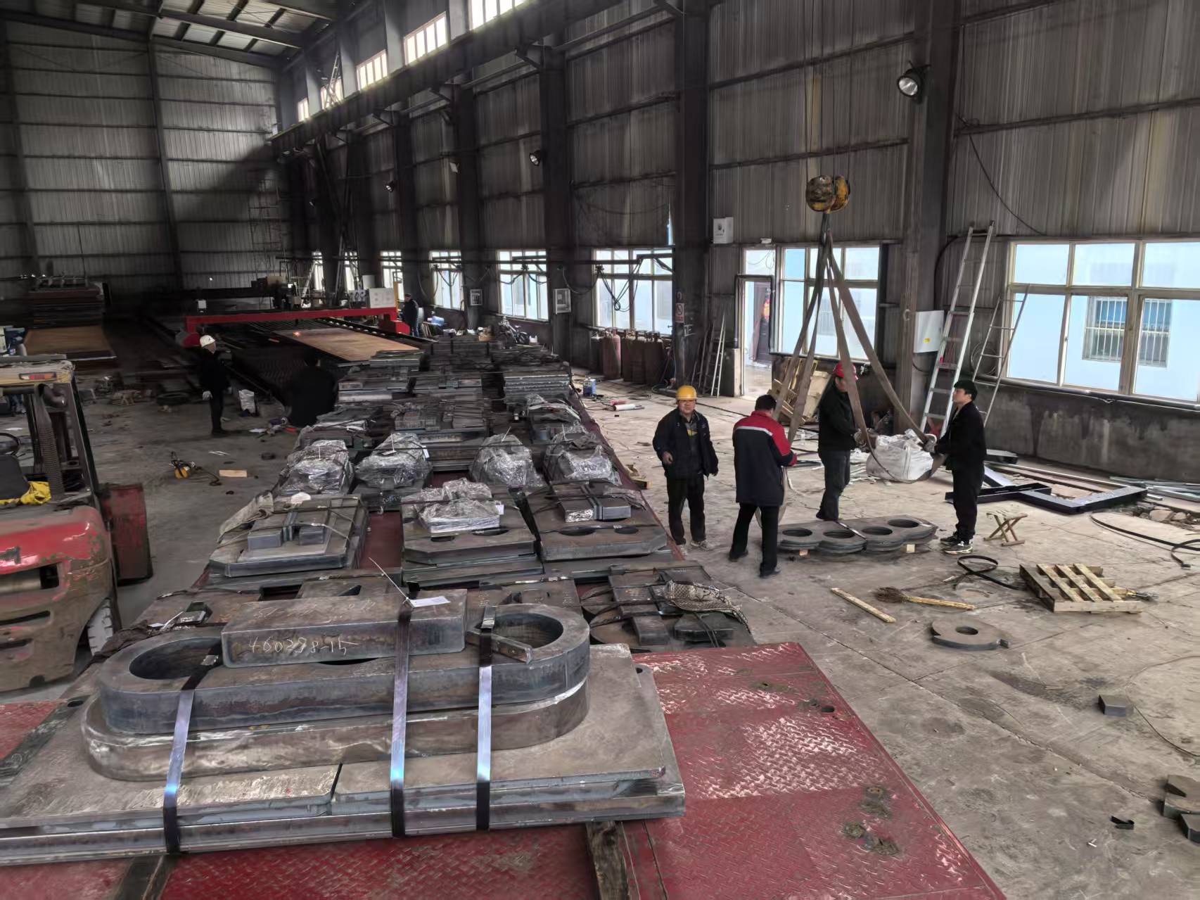 Workshop sorting and packaging finished steel cutting products for worldwide industrial clients Factory workers packing finished custom laser cut steel components ready for global export delivery